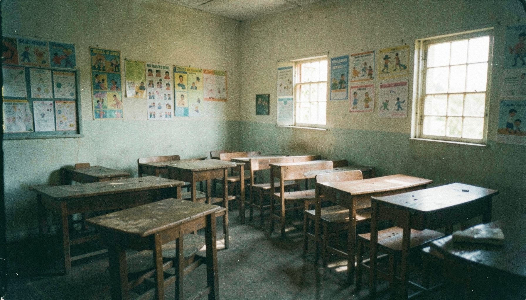 A warm analog film photograph with visible grain showing a sunlit Ghanaian primary classroom interior with wooden desks
